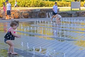 young girl playing in water feature