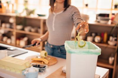 Woman throwing food scraps into kitchen pail
